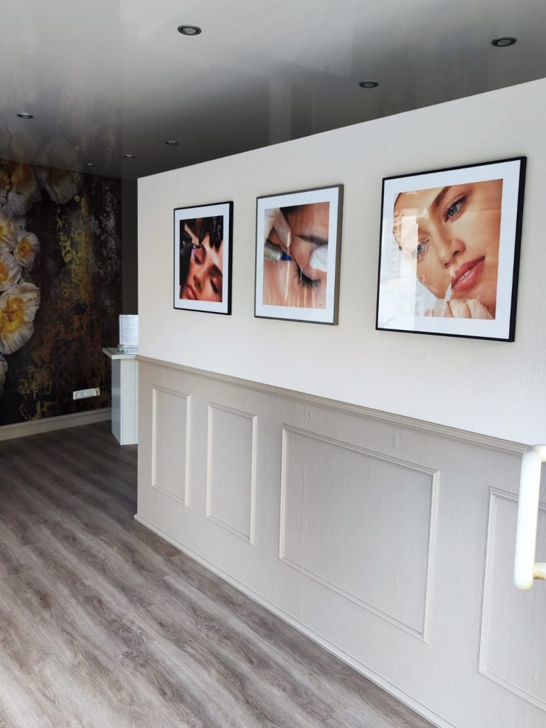 Eine helle Wand mit drei gerahmten Portraits und einem modernen Empfangsbereich.