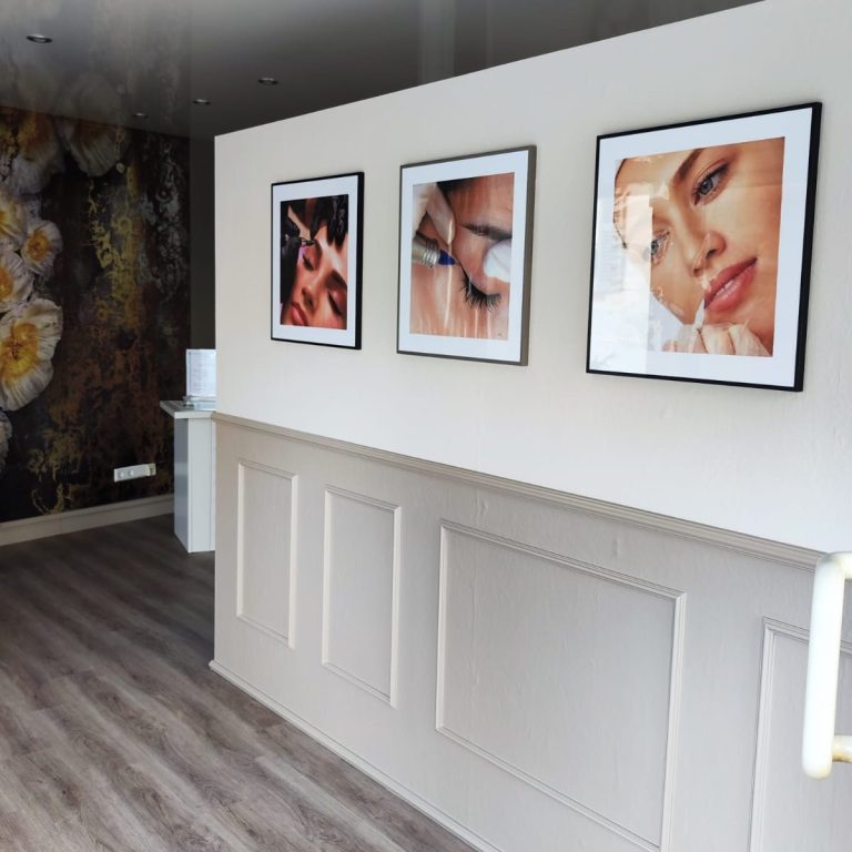 Wand mit drei gerahmten Portraits von Augen und Gesicht in modernem Raum.